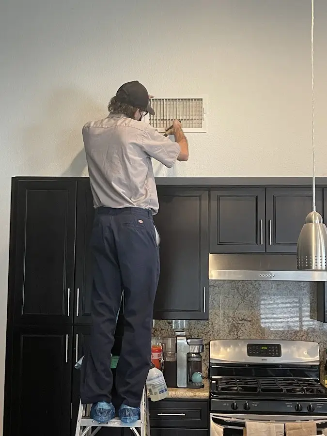Technician inspecting an air vent during HVAC service in Oshtemo